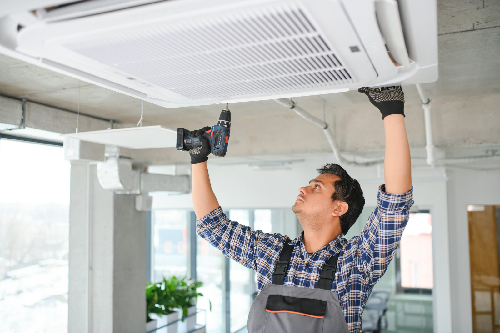 Portrait of young male technician repairing air conditioner. Air conditioner repairs.